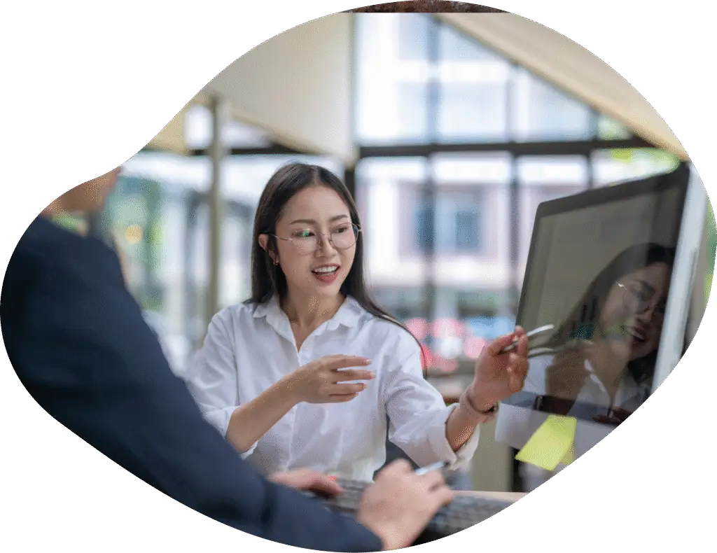 Woman with glasses demonstrating on big computer screen.