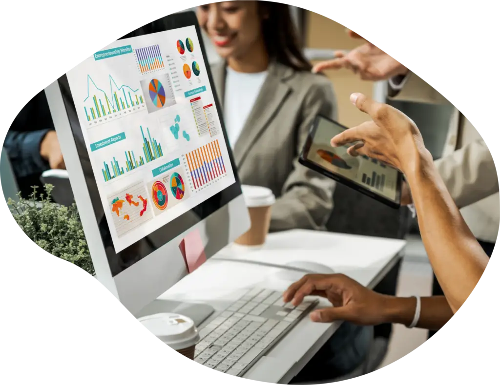 iMac display various charts and graphs as coworkers hands displayed pointing at screen.