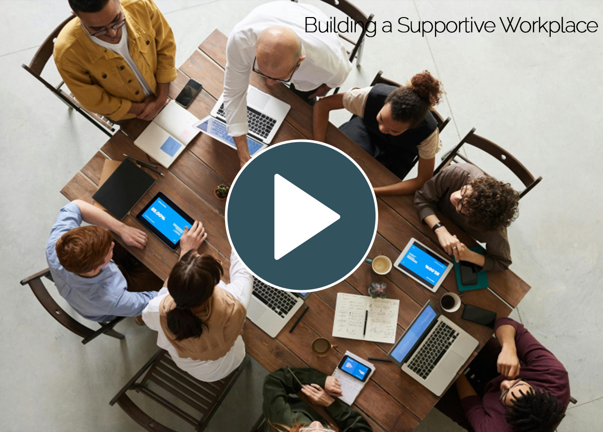 Intro video thumbnail for 'Building a Supportive, Inclusive Workplace' course, showing a diverse team collaborating around a table with laptops and tablets.